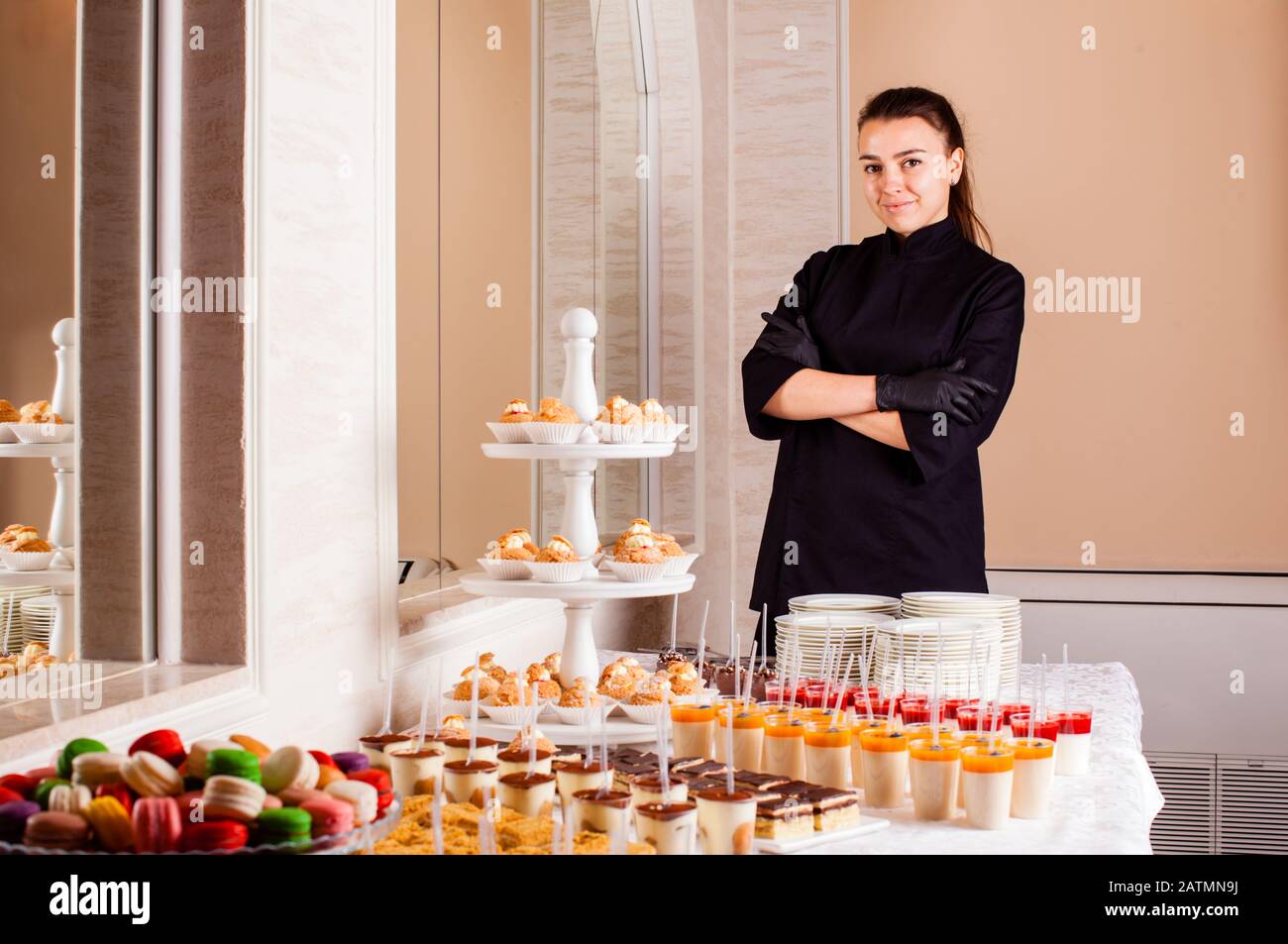 Pastry chef standing near dessert table in restaurant. Woman makes