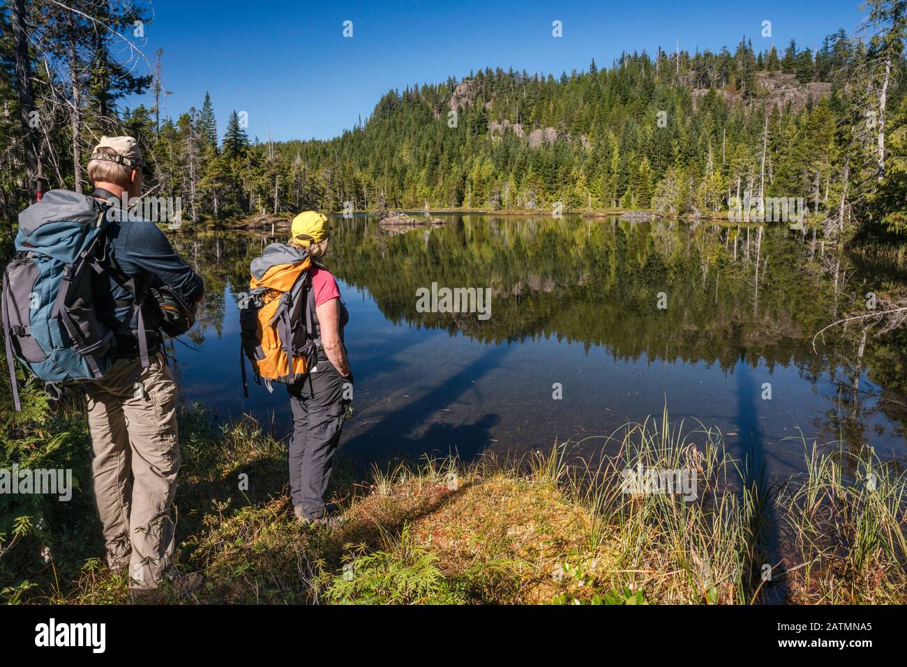 Senior hikers at Little Nugedzi Lake in temperate rainforest, Quadra Island, British Columbia, Canada Stock Photo