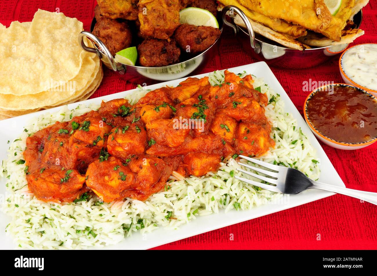 Chicken curry meal with rice and a selection of sides and dips Stock Photo