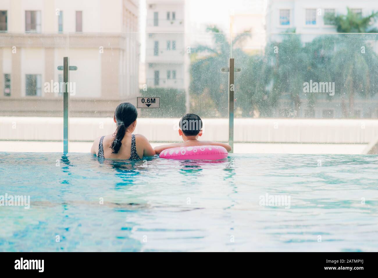 Mother and son in outdoor swimming pool with city view. Stock Photo