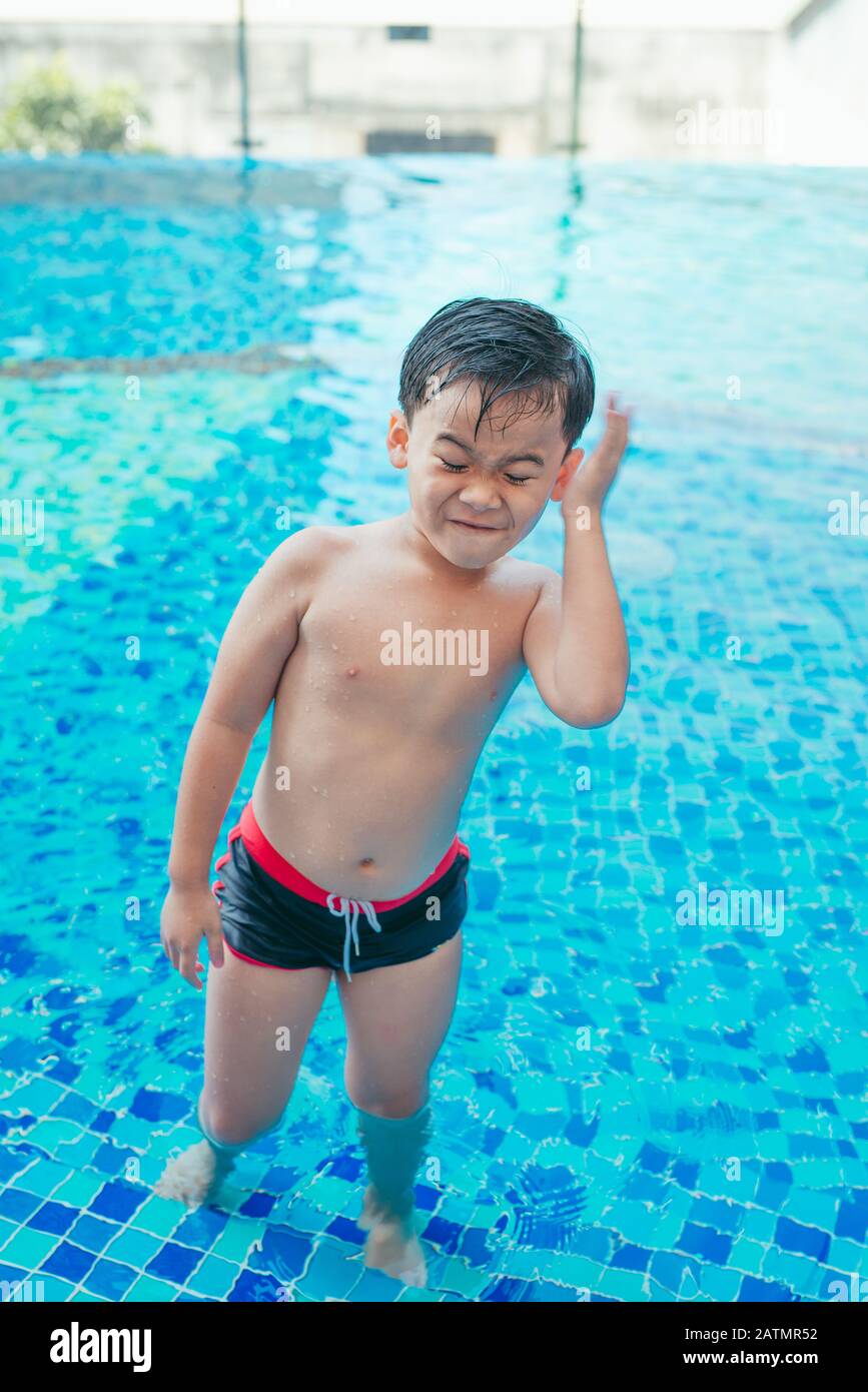 Cute asian kid cleaning ears after swimming in a pool Stock Photo Alamy