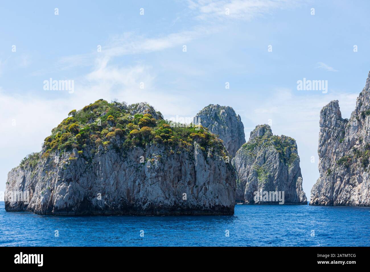 The famous Faraglioni rocks from Capri island, Italy. Sunny summer weather with blue sky and white clouds. Stock Photo
