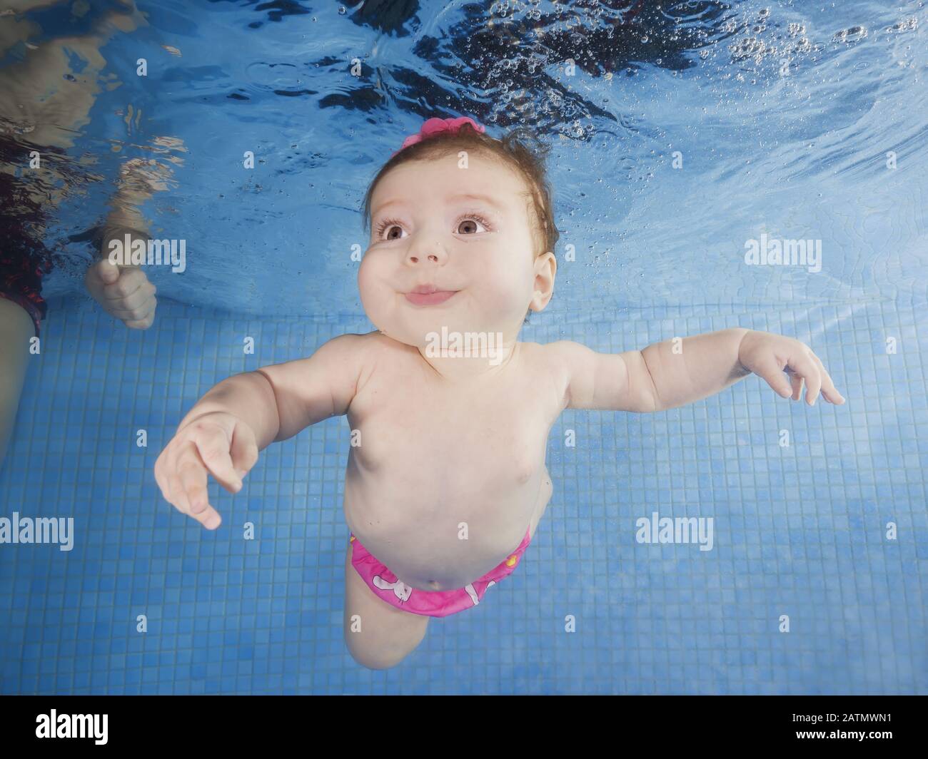 Little baby learning to swim underwater in a swimming pool hires stock