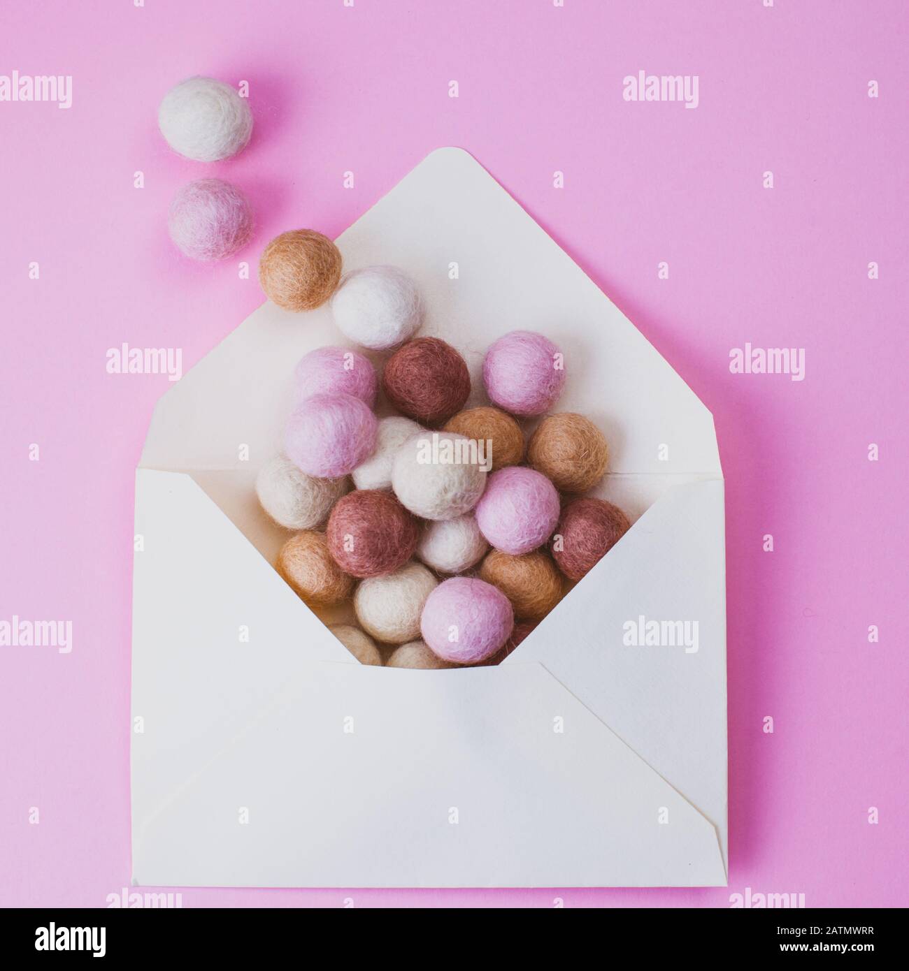 Freedom concept. Felt balls fly out from envelope over pink background. Stock Photo