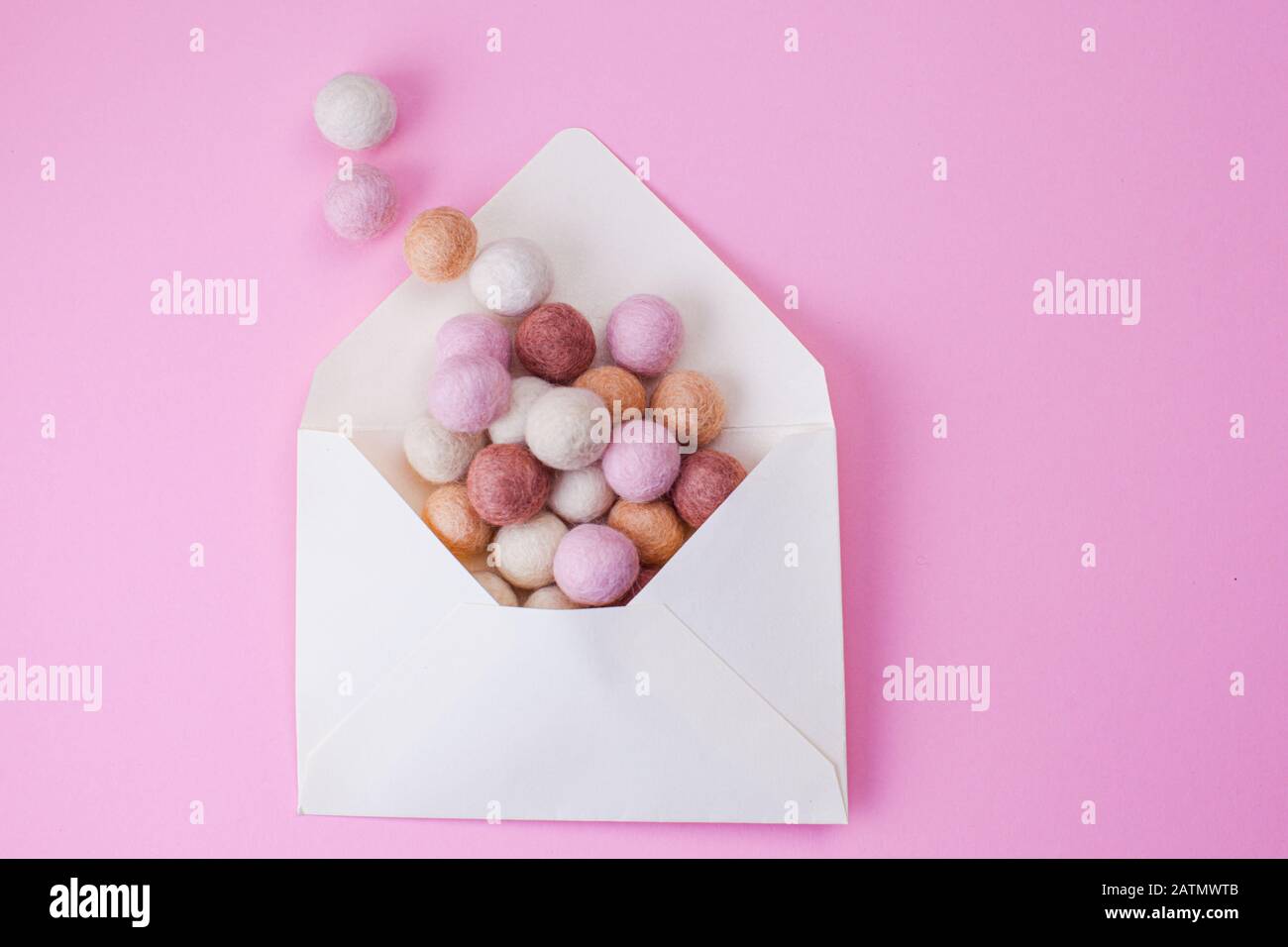 Colorful handmade felt balls fly out of paper envelope. Message, mail and letter concept Stock Photo