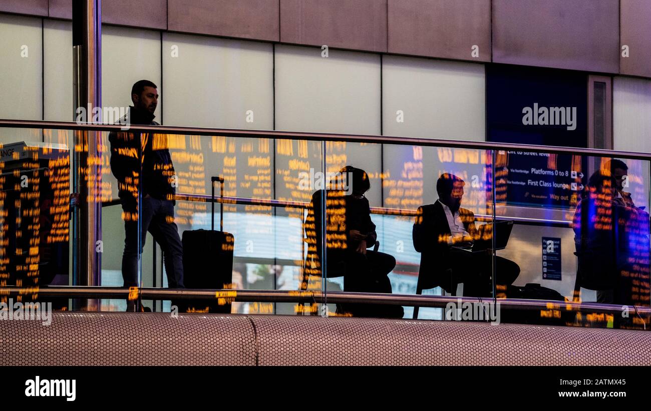 Waiting for a Train. Passengers watch the departure boards at Kings Cross Railway Station in Central London, Stock Photo