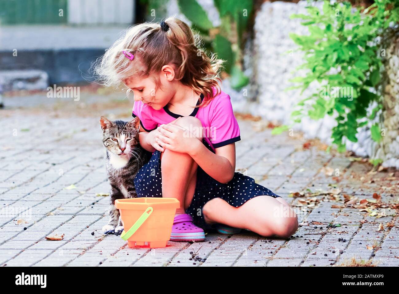 Girl sitting next to a cat on the street . Yalta. Crimea. Stock Photo