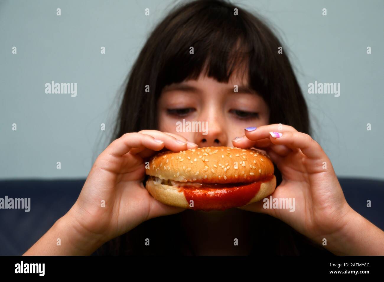 6 year old girl eating a chicken burger hires stock photography and
