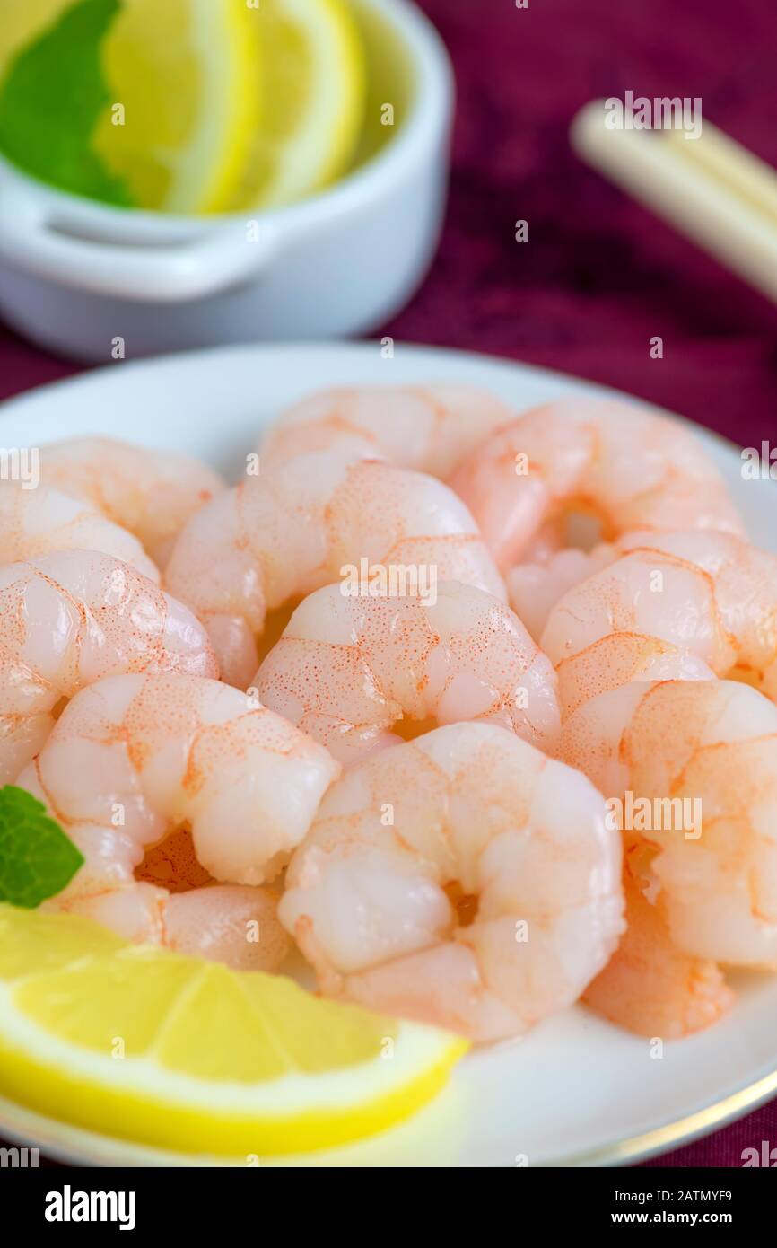 succulent fresh cooked whole king prawns peeled  with lemon and mint on a dish  blurred background for copy space Stock Photo