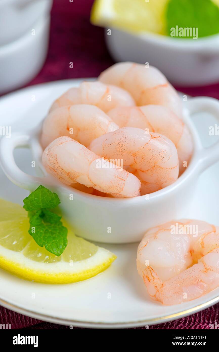 healthy fresh king prawns peeled and cooked whole with lemon and mint on a dish,  blurred background for copy space Stock Photo