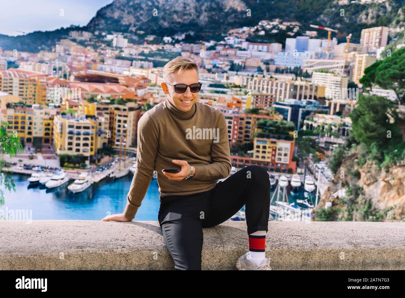 Man Using Camera Monaco young man sitting on seaside pier in Monaco. enjoing panoramic view ...
