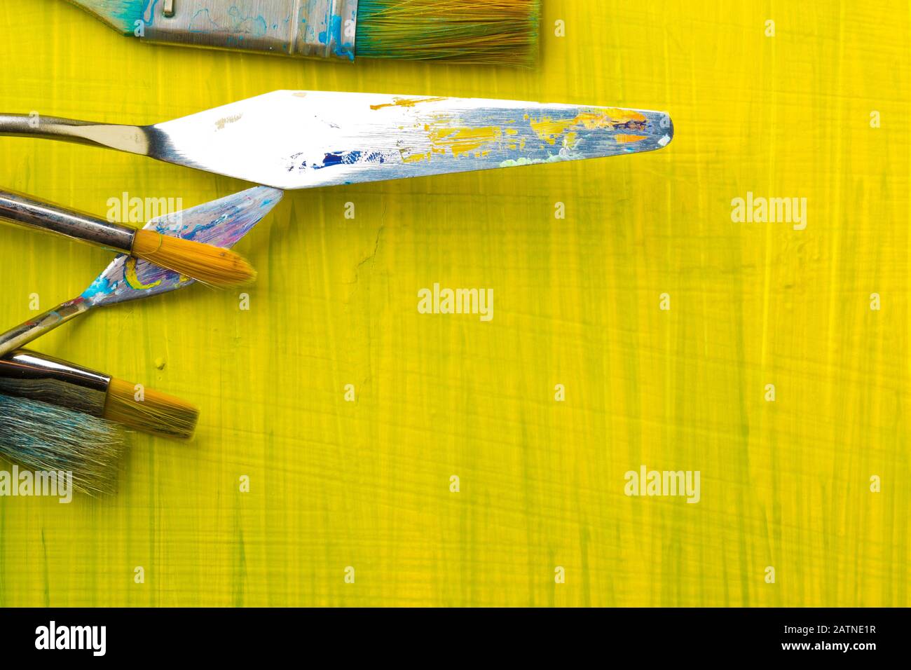 Artistic art supply utensils with paintbrushes on yellow canvas background with copy space flat lay top view from above Stock Photo