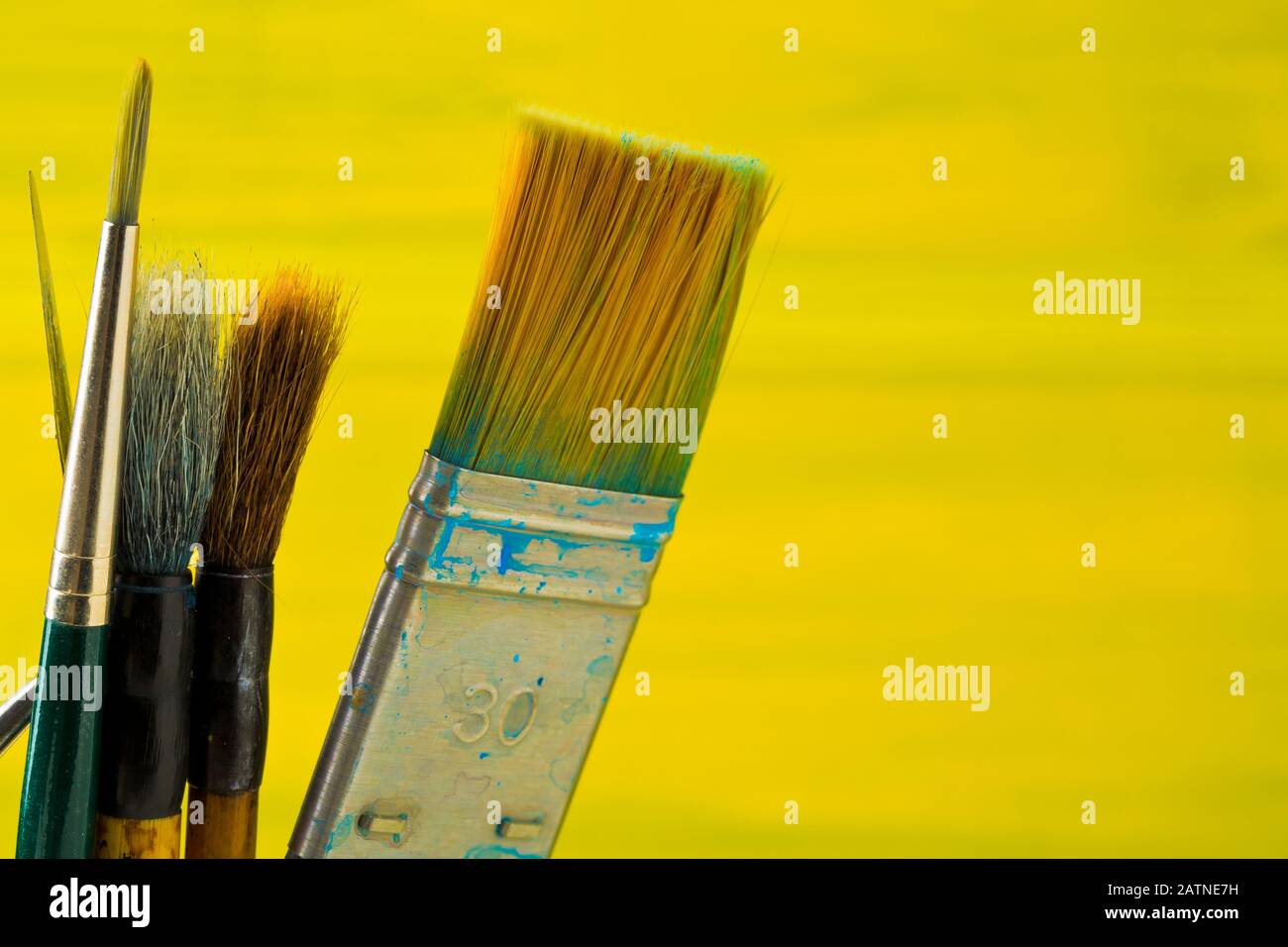 Artistic art supply utensils with paintbrushes on yellow canvas background with selective focus Stock Photo