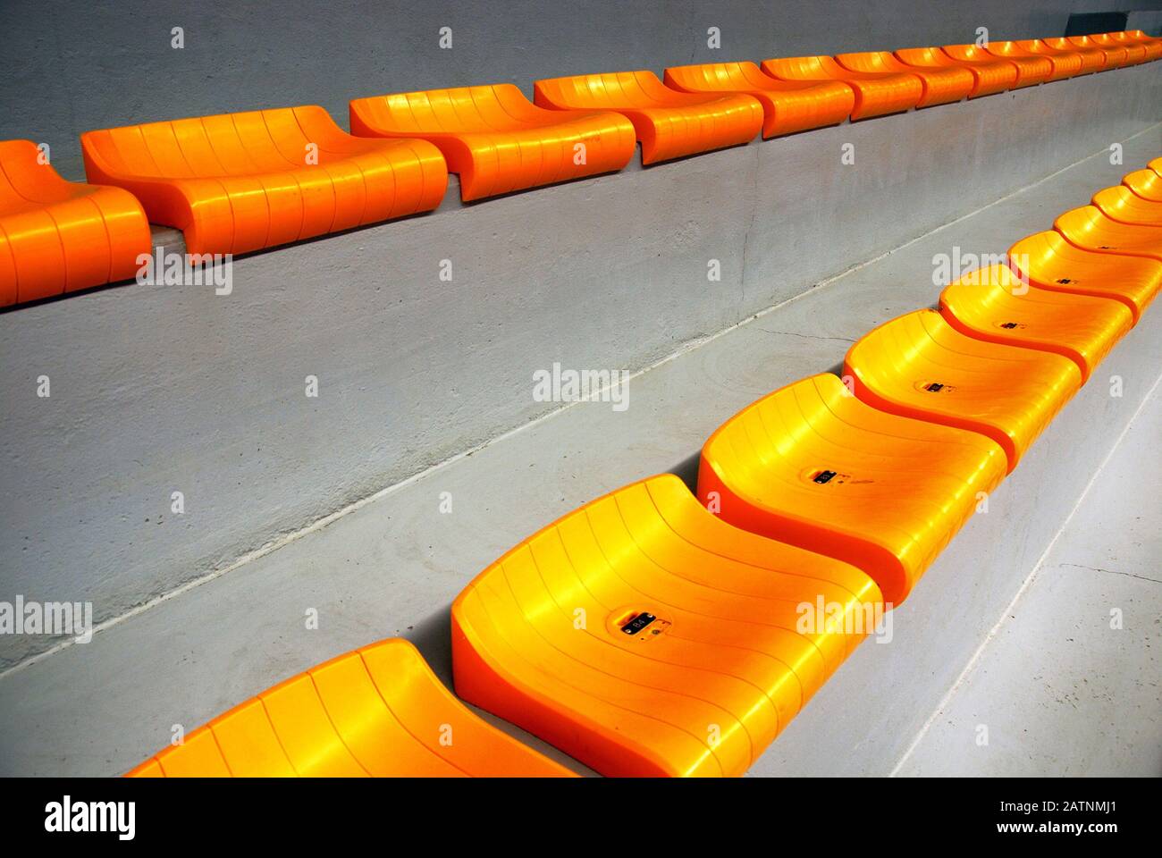 Rows of empty orange plastic seats at stadium Stock Photo