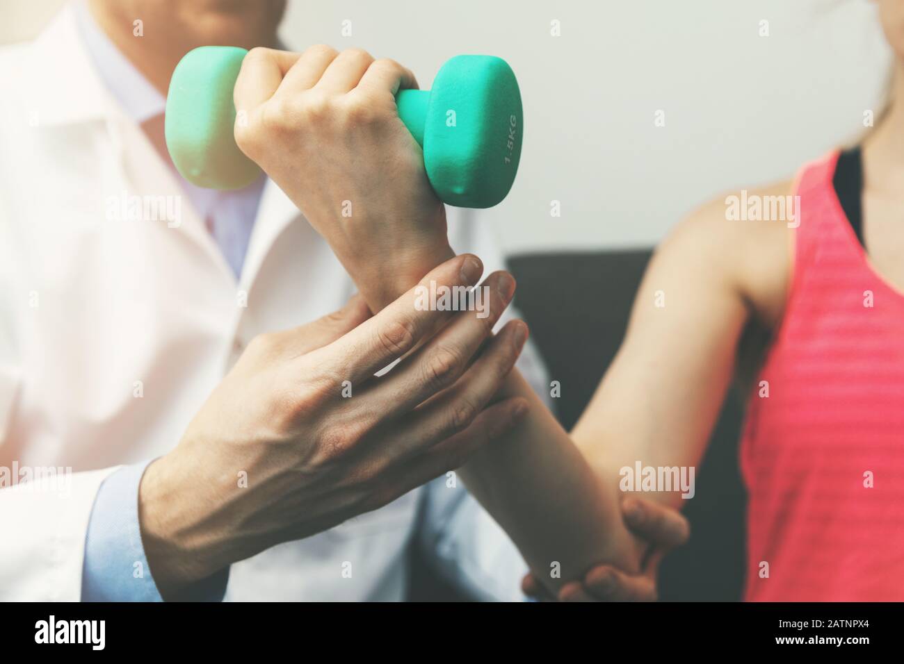 physiotherapy - physiotherapist help woman patient to recover from hand injury at home. dumbbell exercises Stock Photo