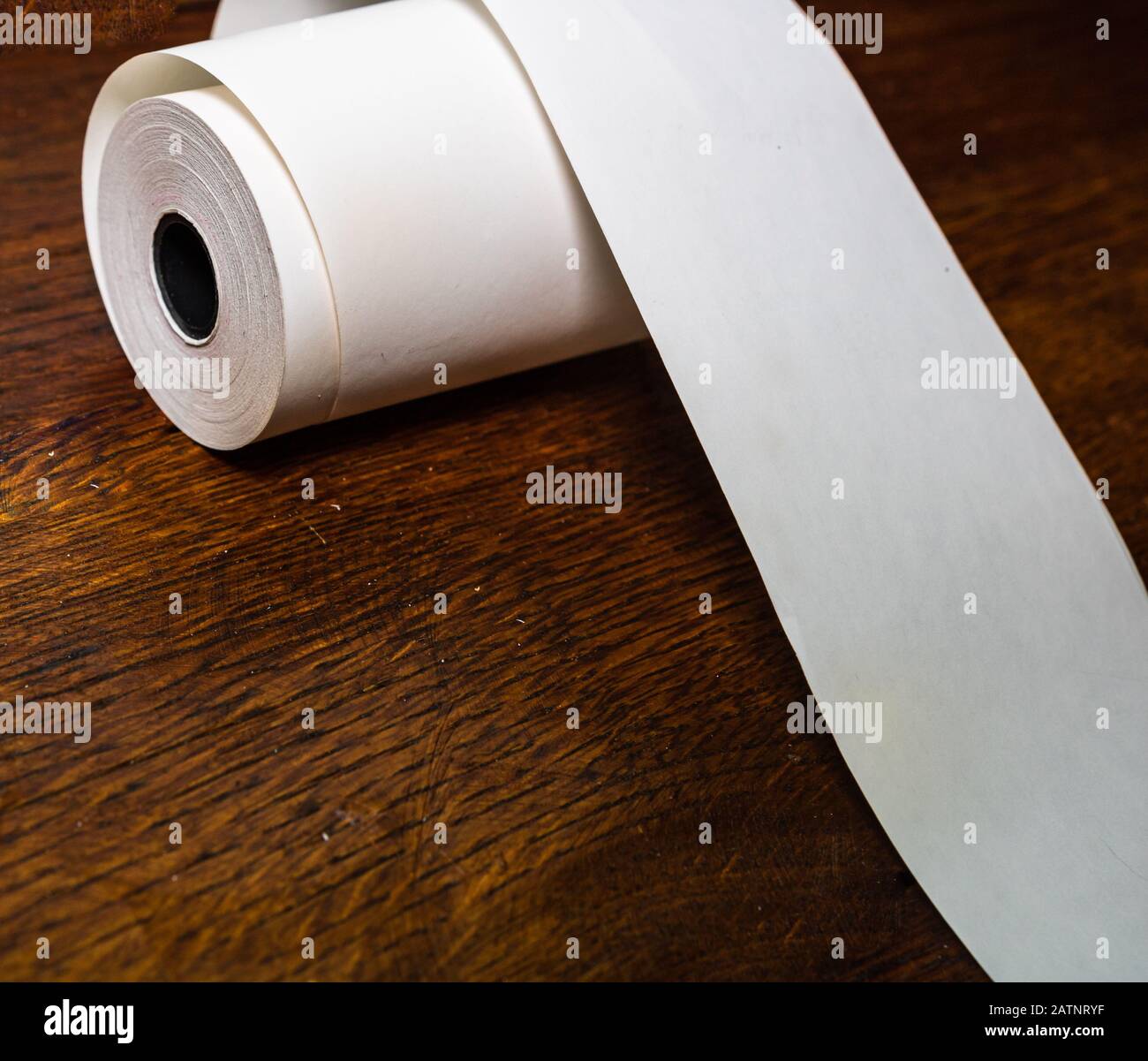 Roll of cash register tape, empty blank tax receipt on table isolated