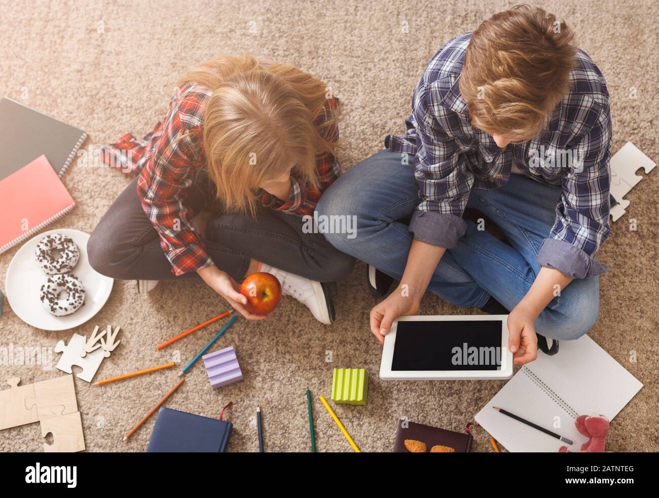 Brother And Sister Using Digital Tablet Sitting On Floor, Above-View Stock Photo