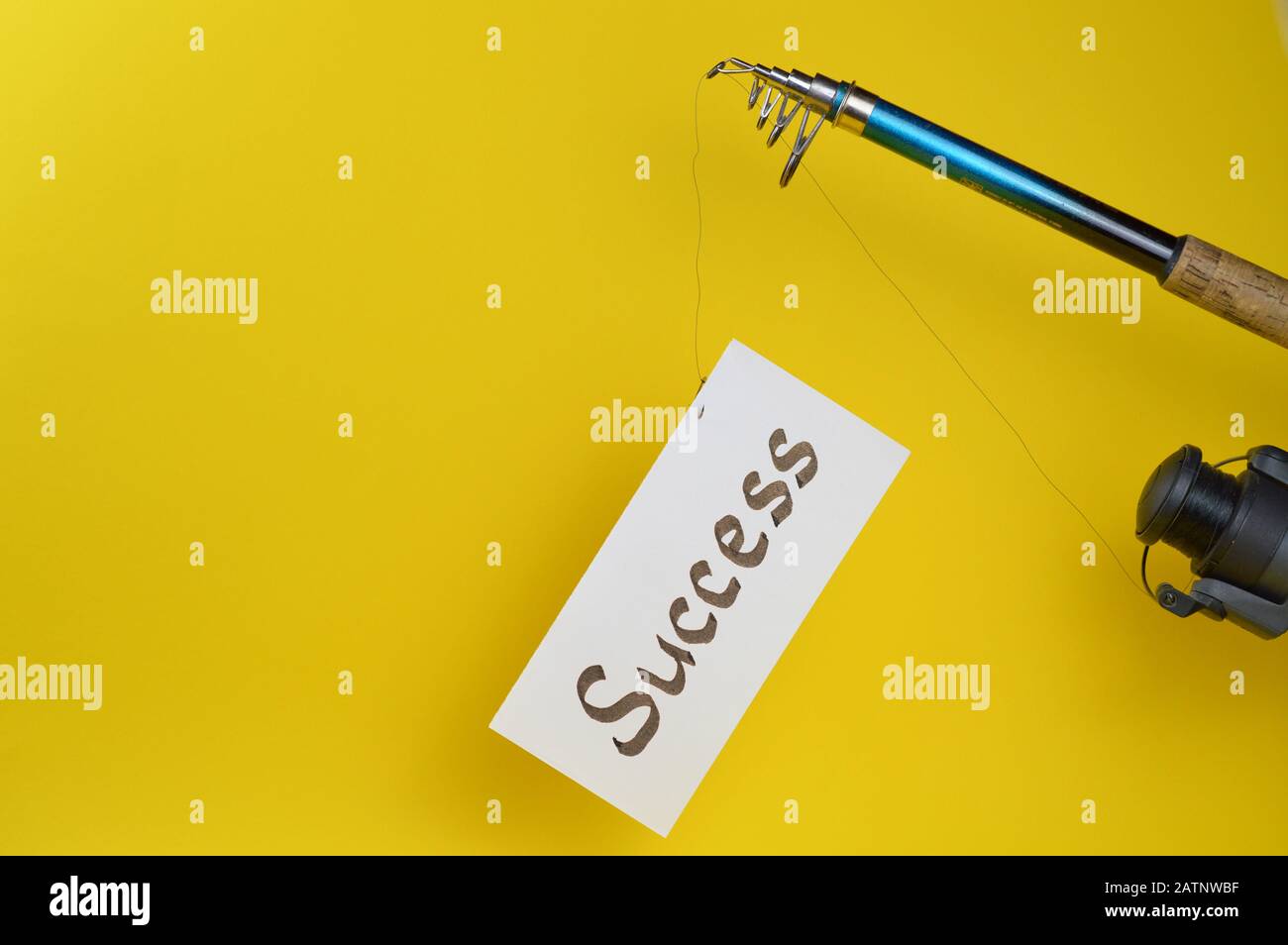 fishing line with piece of paper hanging of as symbol for temptation in front of yellow background Stock Photo