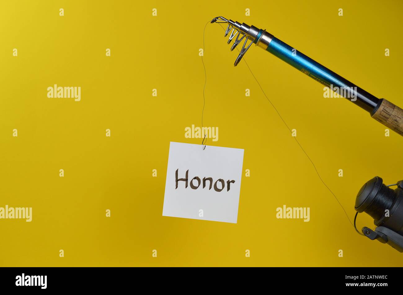 fishing line with piece of paper hanging of as symbol for temptation in front of yellow background Stock Photo