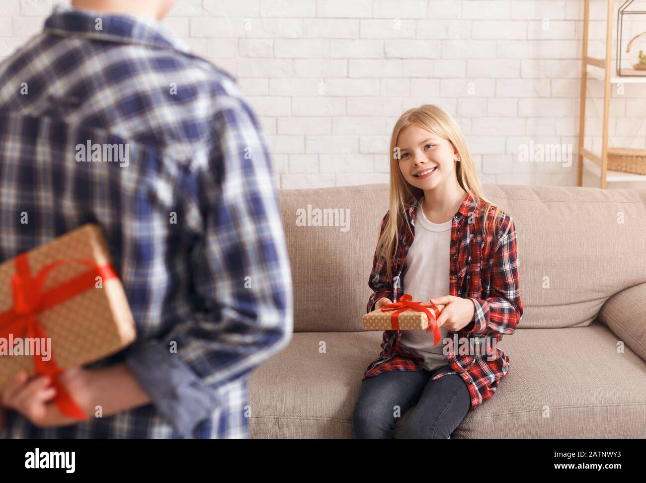 Unrecognizable Boy Holding Gift Congratulting Sister On Birthday At Home Stock Photo