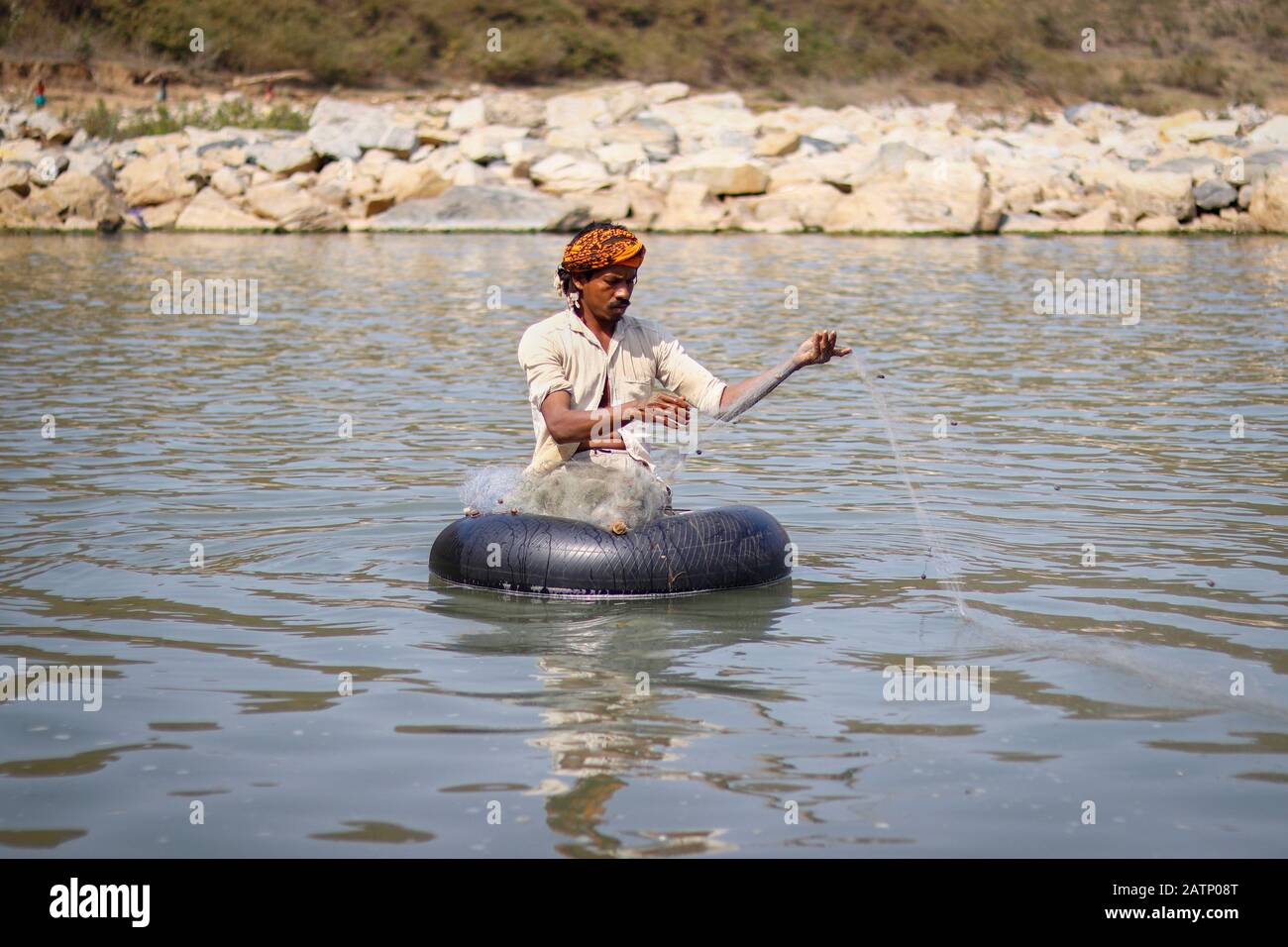 Halon India Feb 02. 2020 : While fishing, the fisherman sits in a tire tube in the halon dam and lays the net. Stock Photo