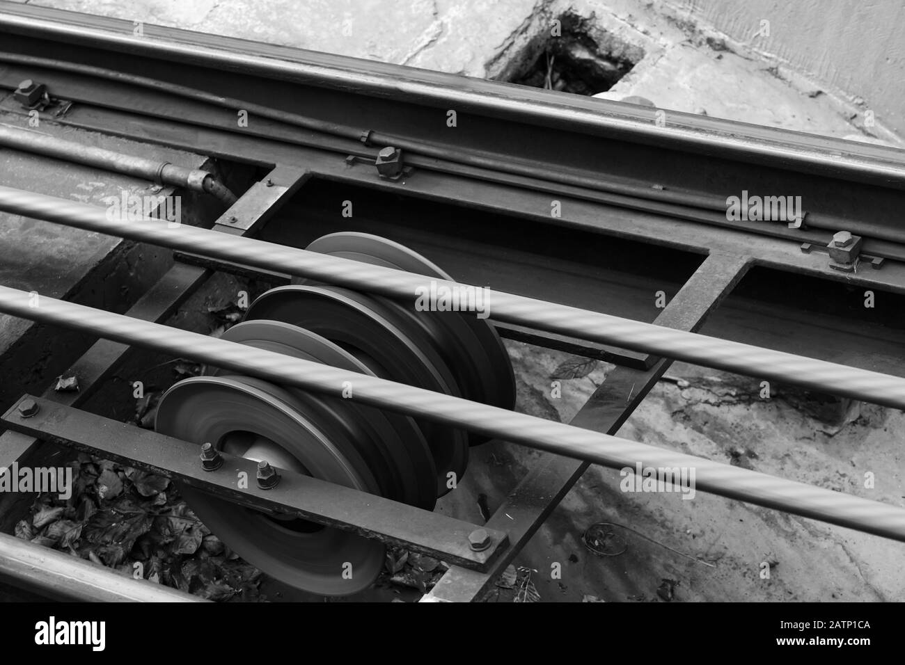 Funicular details. Rails, moving traction cable and support rollers. Black and white photo Stock Photo