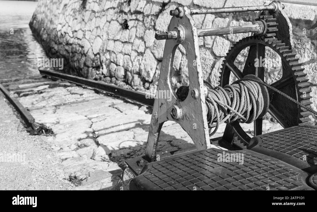 Old rusted winch for lowering and raising boats to water in the port. Black and white photo Stock Photo