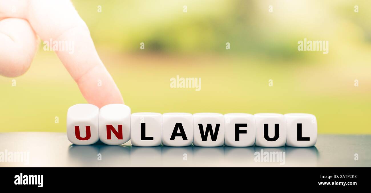 Hand turns dice and changes the word 'unlawful' to 'lawful'. Stock Photo