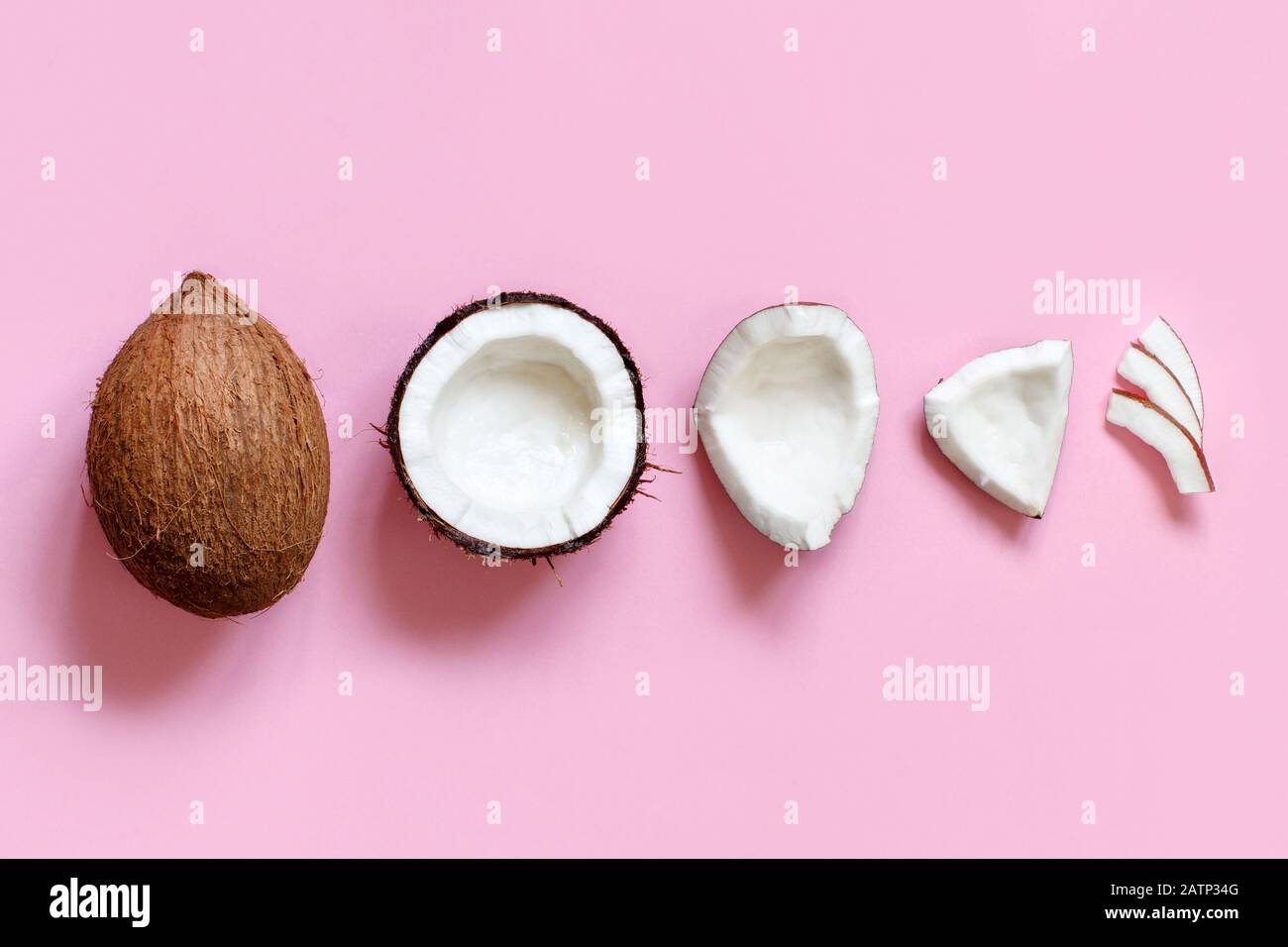Ehole coconut and coconut pieces on a light pink background top view Stock Photo