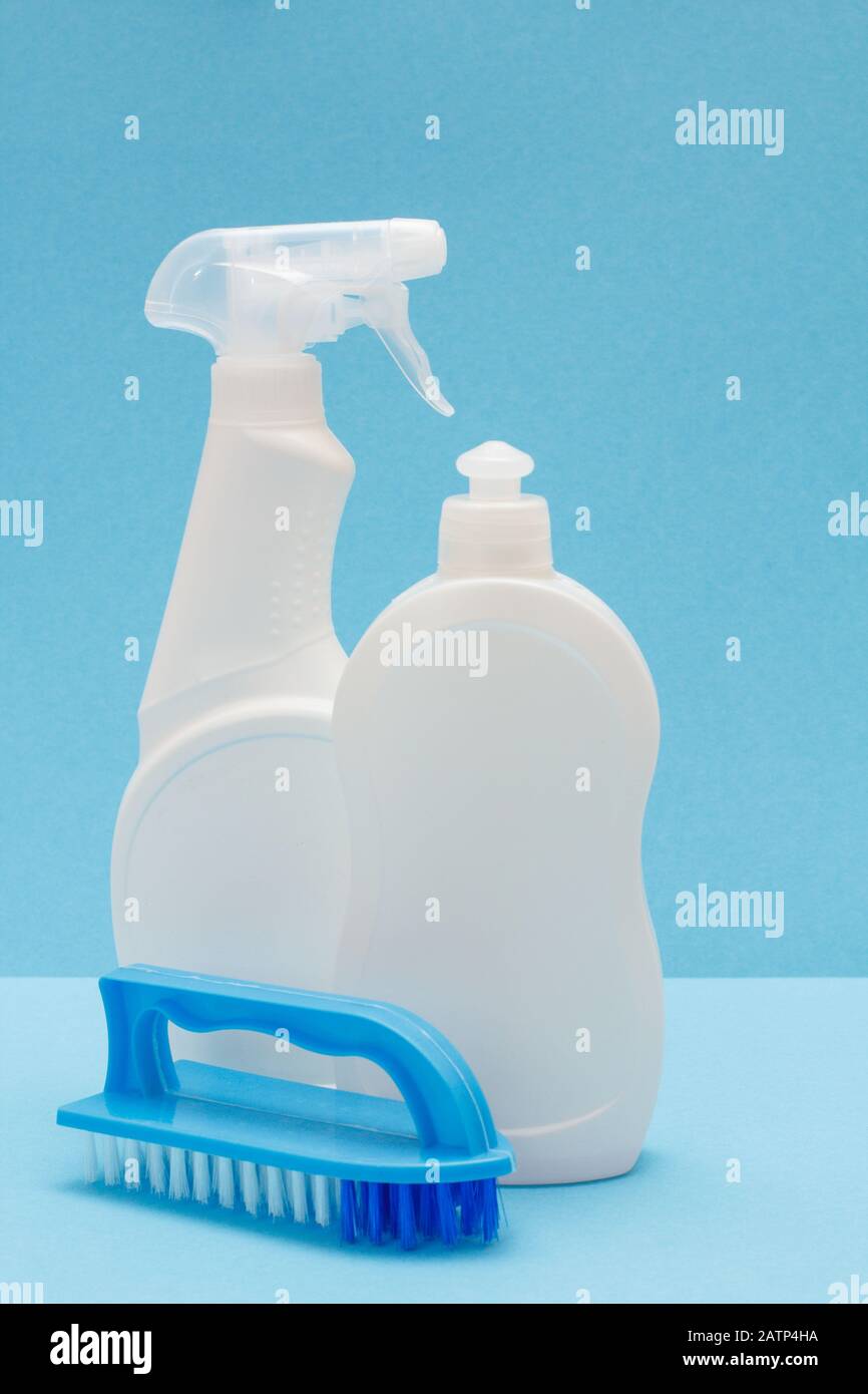 Bottles of dishwashing liquid, glass and tile cleaner, brush on blue