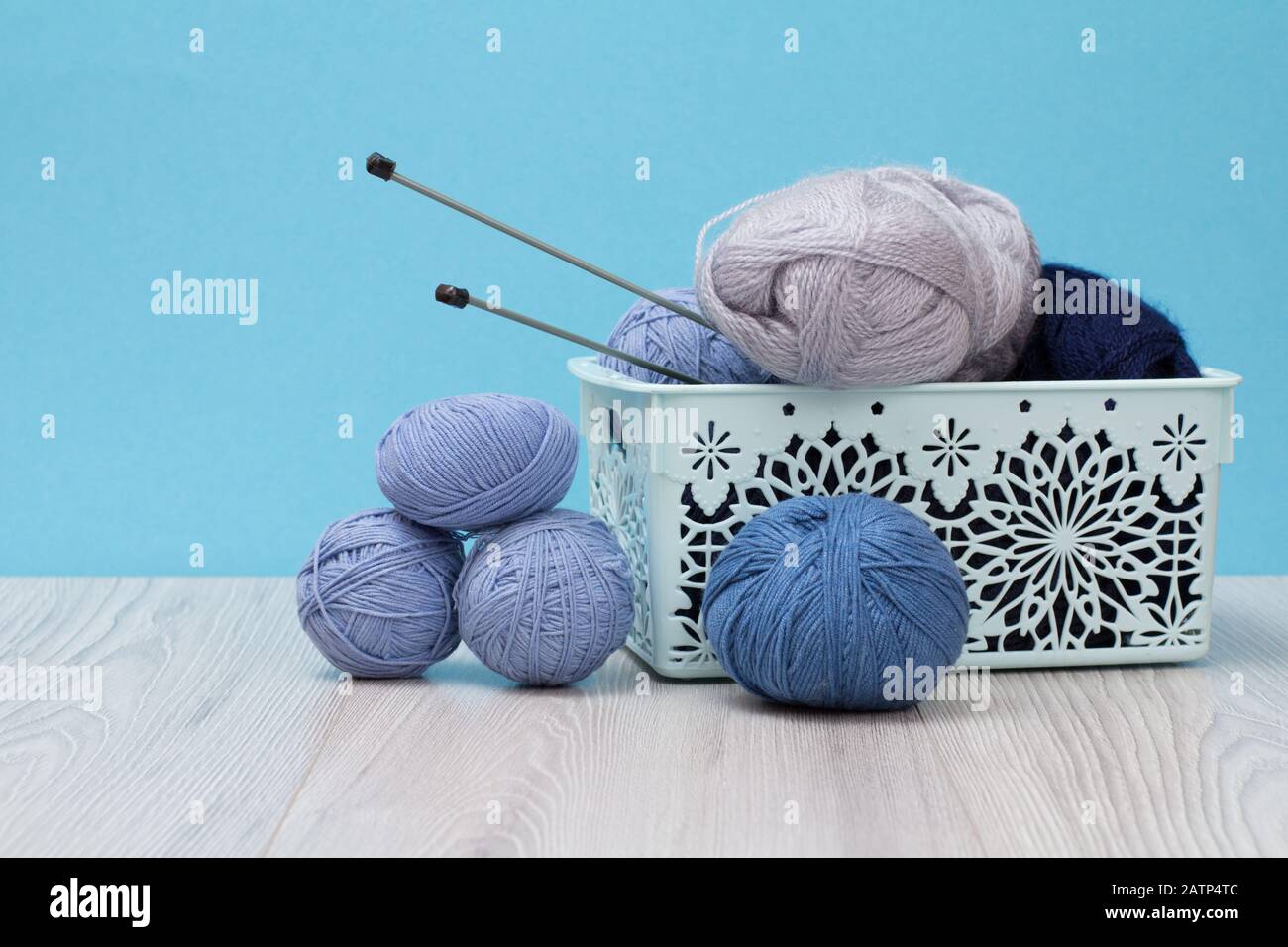 Knitting yarn balls and metal knitting needles in plastic basket on ...