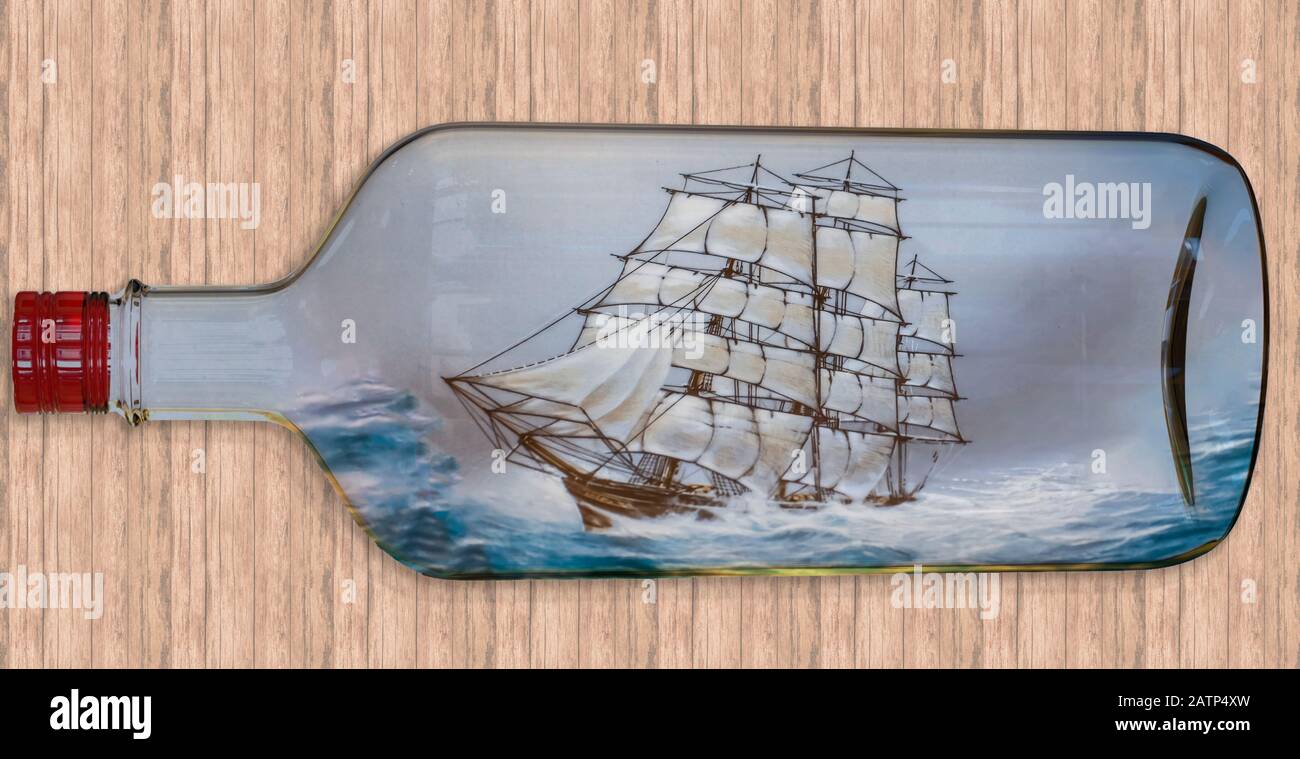 Digitally created image of a tall ship with full sail sailing in a rough sea inside a transparent bottle Stock Photo