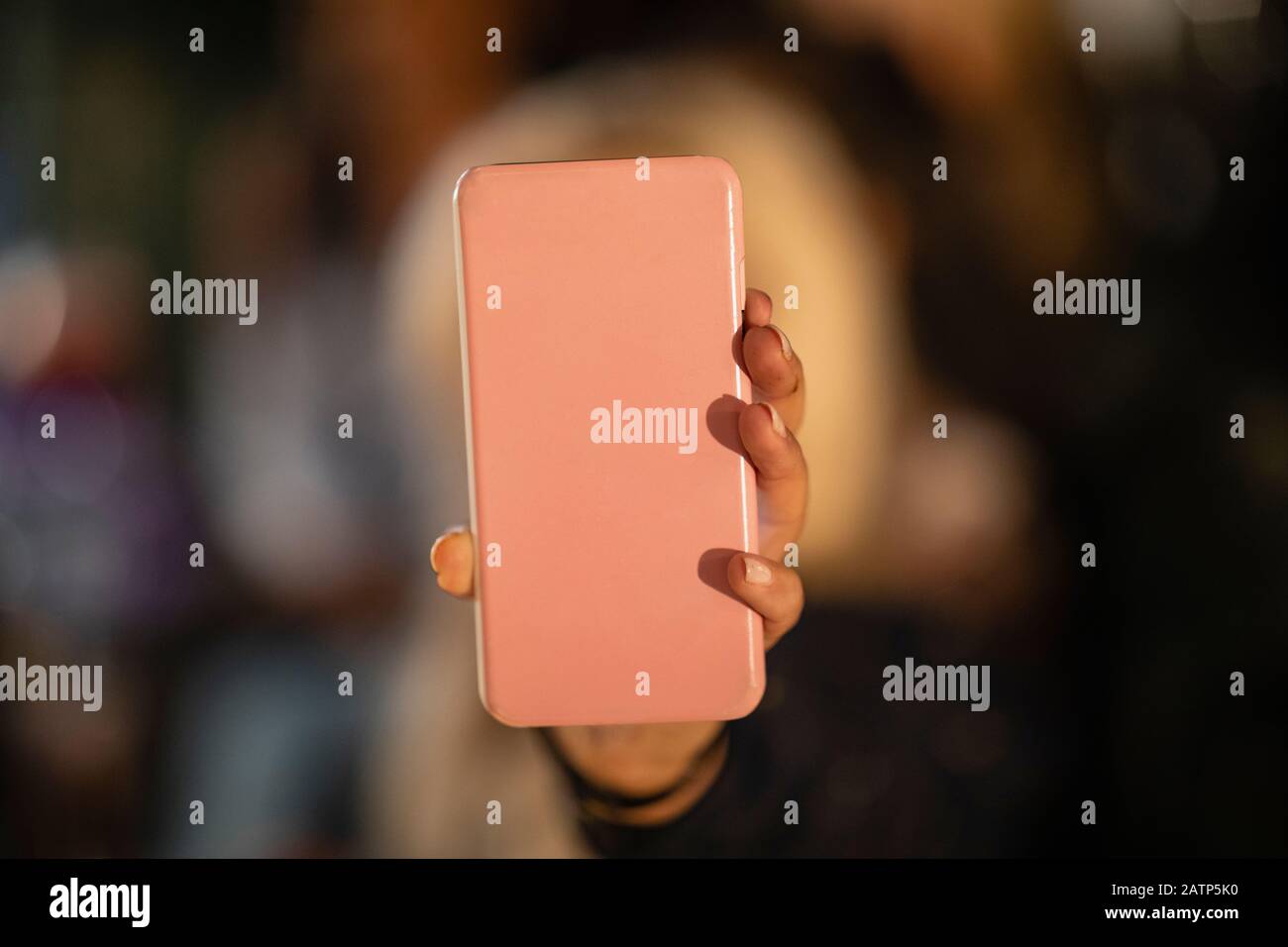 An unrecognizable person holding a phone up to the camera with a phone case on. Stock Photo