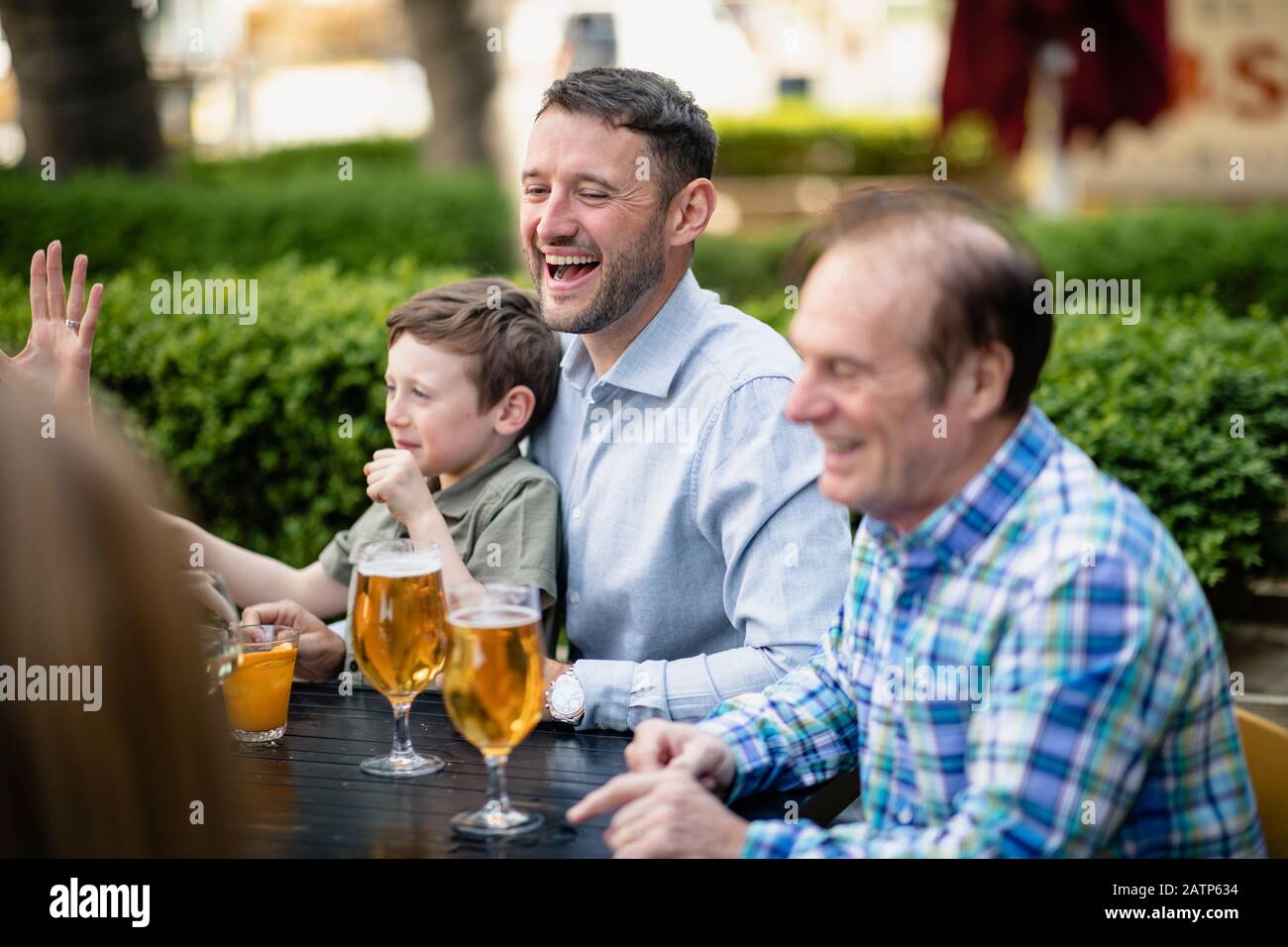 A multi-generation family having a drink together outdoors at a bar. Stock Photo