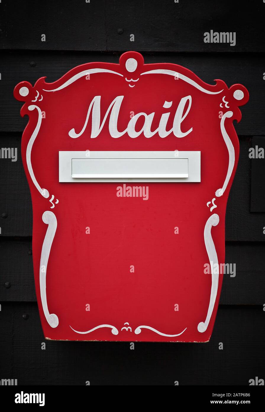 Traditional, red wooden handcrafted mailbox with the letters Mail handpainted on the front Stock Photo