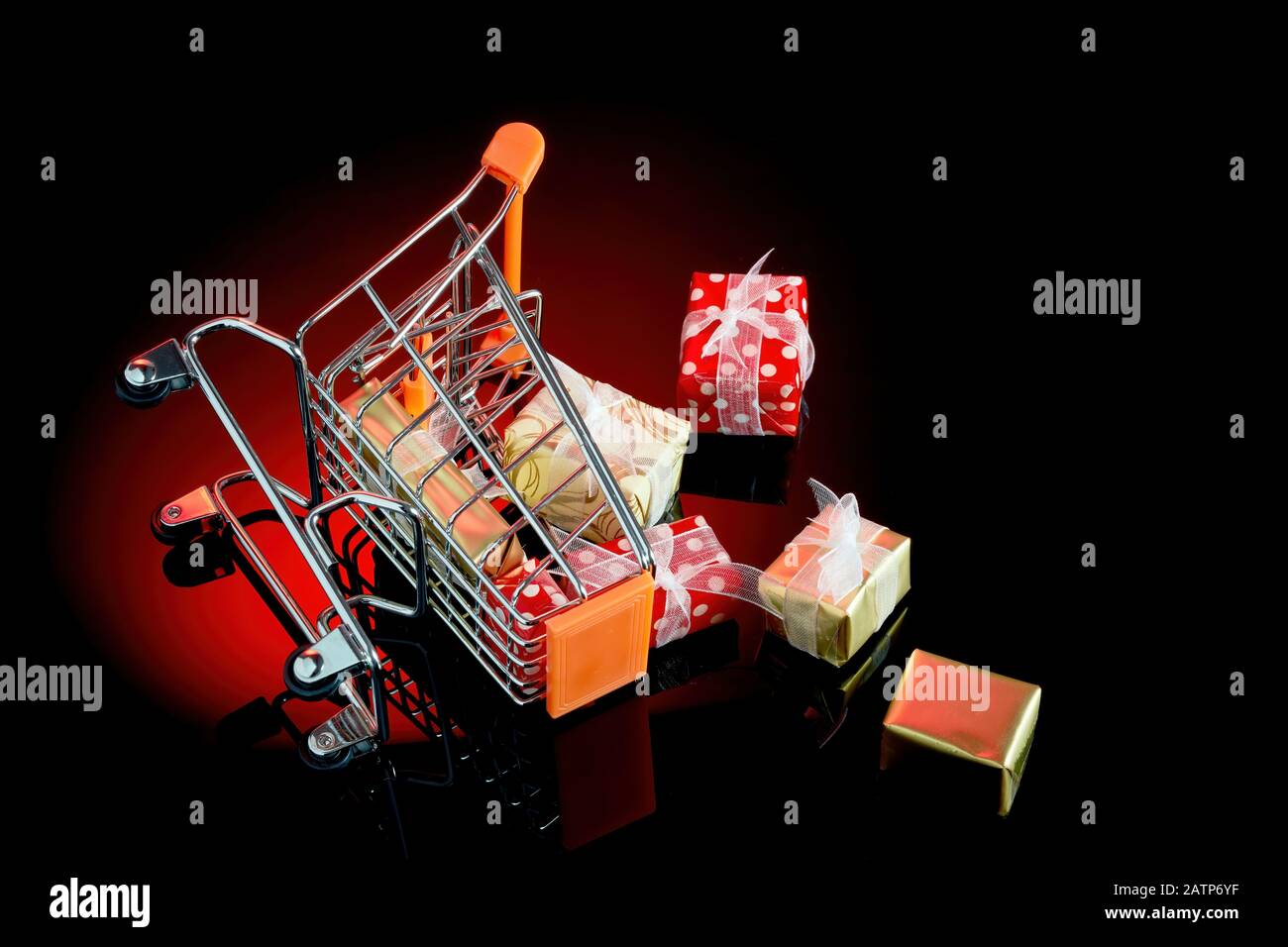 Toppled shopping cart with gift boxes spilled all over the floor with copy space. Concept of consumerism and compulsive spending or buying disorder. Stock Photo
