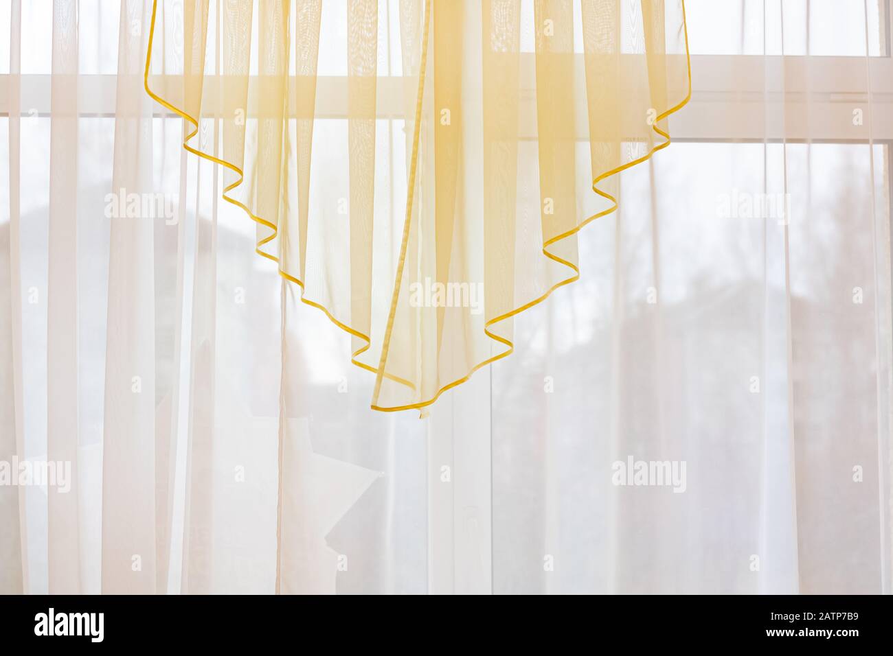 Delicate yellow tulle on the window, room decor Stock Photo