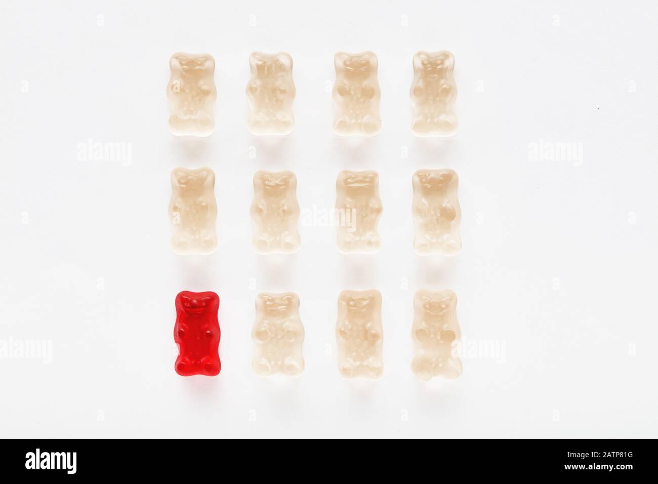 Red gummy bear standing out of the crowd with its distinctive color. Diversity and difference Stock Photo