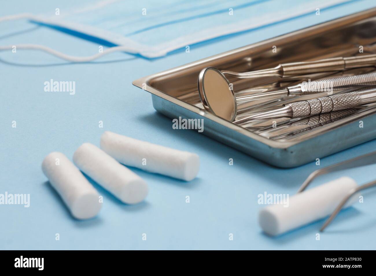 Set of dental instruments for dental treatment. Medical tools in stainless steel tray, protective mask and cotton tampons. Close-up view. Shallow dept Stock Photo