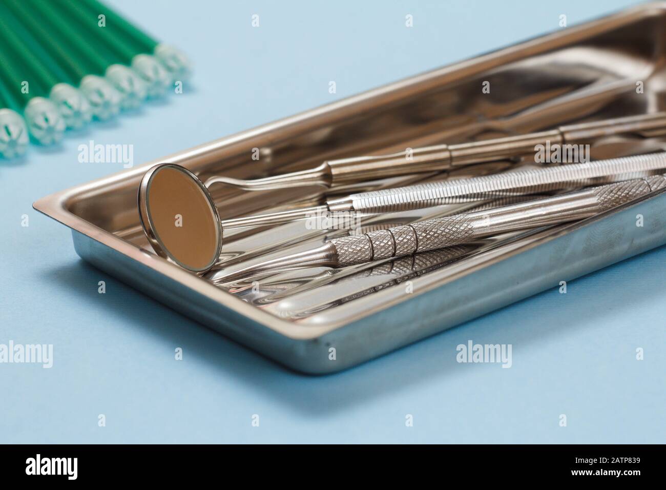Set of metal dental instruments for dental treatment and saliva ejectors. Medical tools in stainless steel tray on blue background. Stock Photo