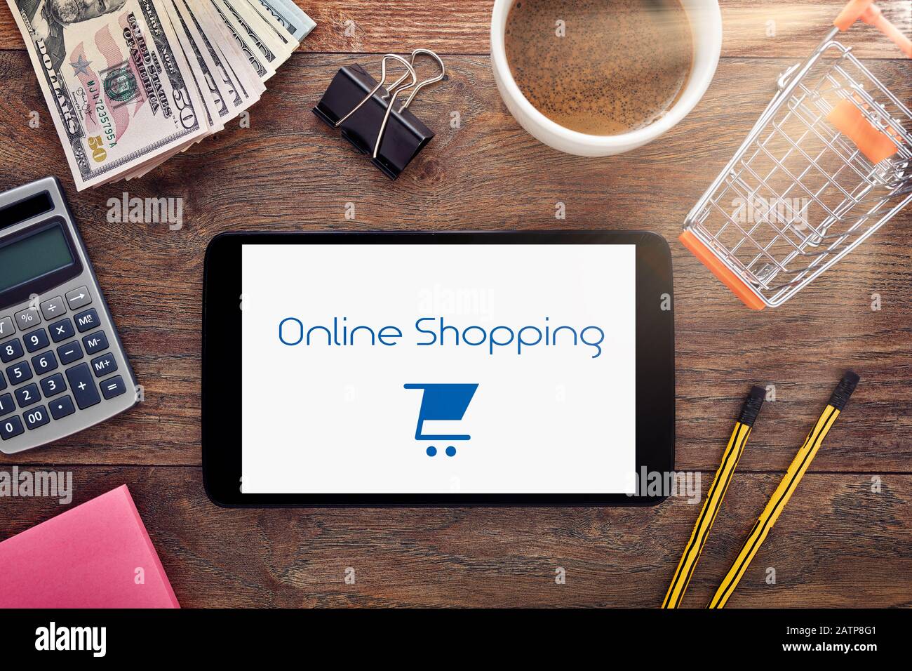 Online internet shopping. Tablet pc, calculator, shopping cart, dollar  bills on a wooden business table. Overhead view Stock Photo - Alamy