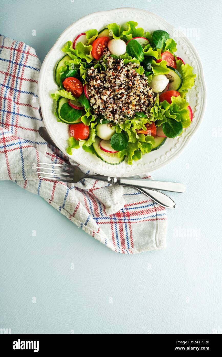 Healthy Green salad meal with fresh vegetables and quinoa seeds on blue table background Stock Photo