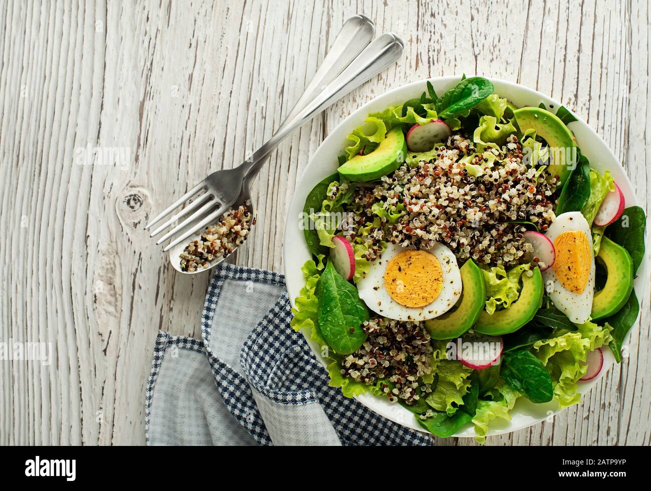 Healthy green salad meal with quinoa, egg and avocado on wooden background Stock Photo