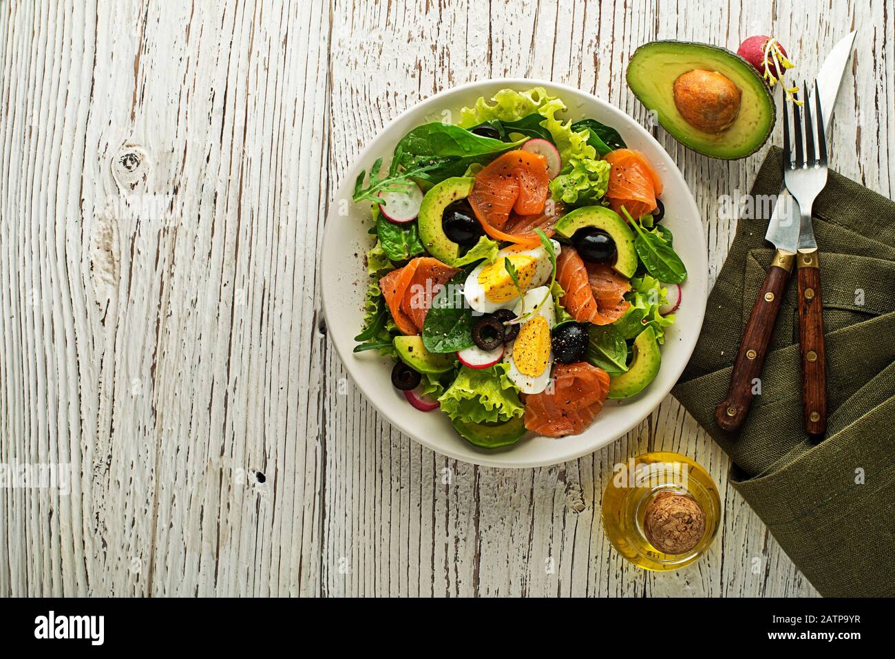 Fresh green lettuce salad with smoked salmon and avocado on wooden background Stock Photo