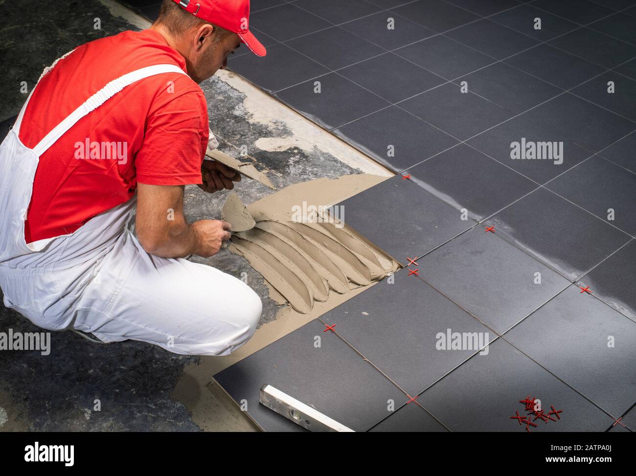 A construction worker putting on new floor tiles Stock Photo - Alamy