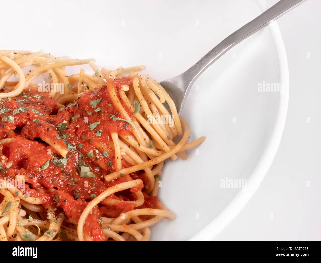 Whole wheat spaghetti macro. Fork in white bowl. Marinara sauce with