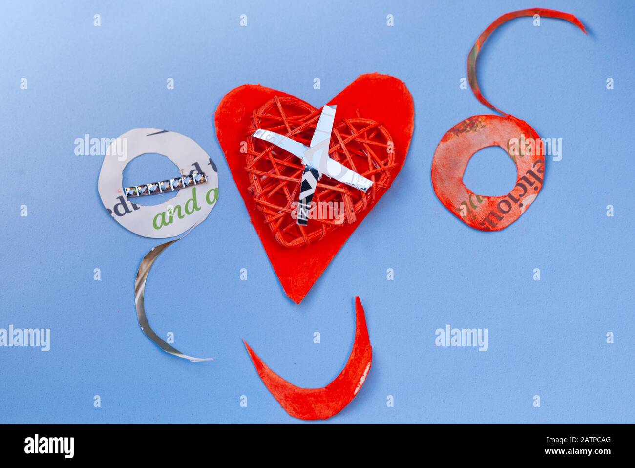 Still life love concept for Valentines Day - OXO and red paper heart & smiling mouth on a light blue background. Copyspace. Stock Photo