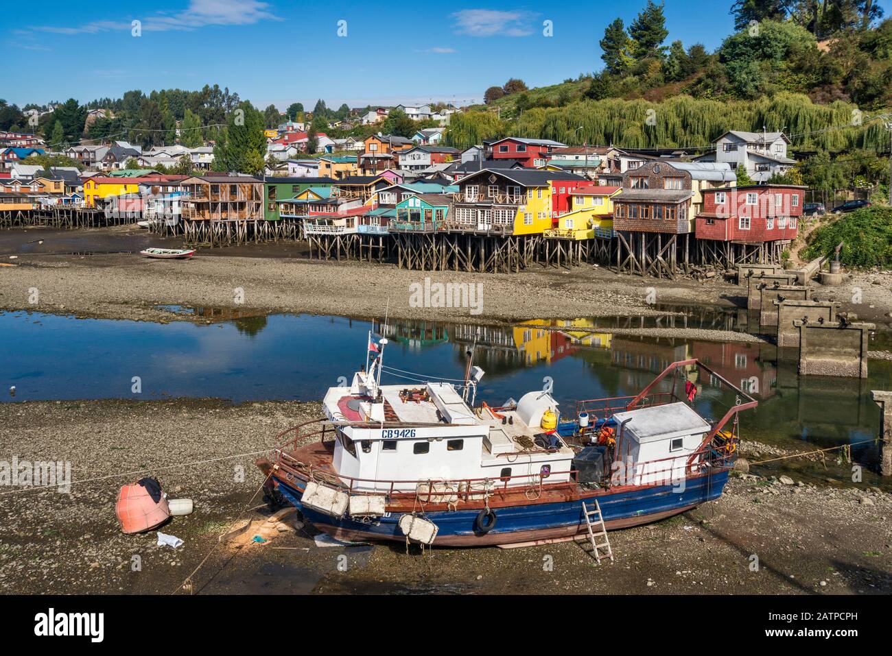 Fishing boat at low tide, palafitos, wooden stilt houses in Castro, Isla Grande de Chiloe, Los Lagos Region, Patagonia, Chile Stock Photo