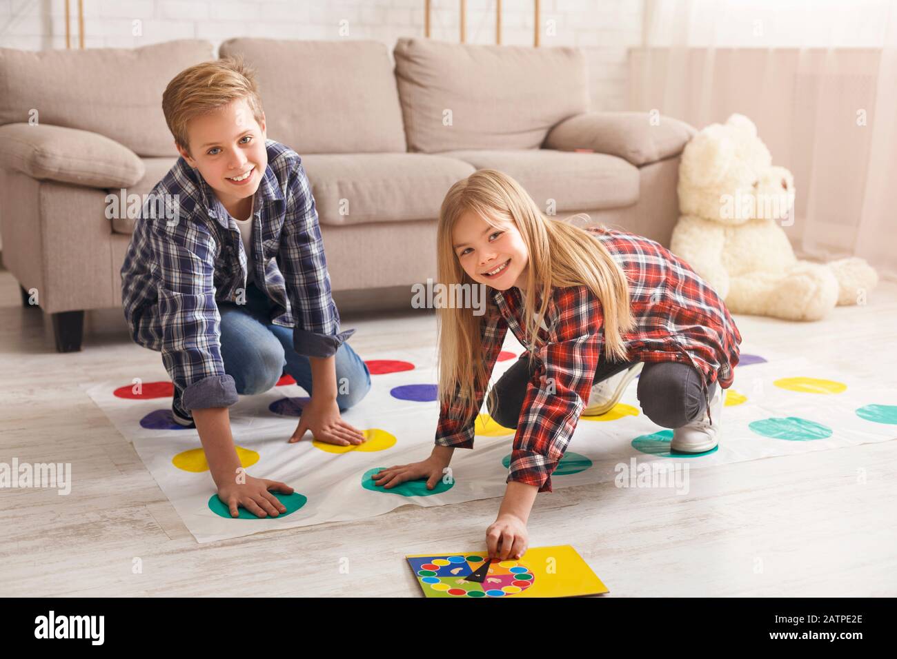 Cheerful siblings playing twister game on floor having fun indoor Stock Photo