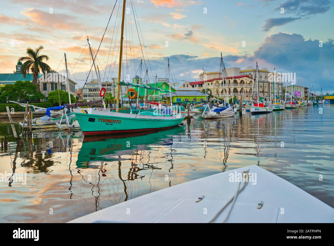 Colourful waterfront of Belize City at dusk with reflections in the tranquil water; Belize City, Belize District, Belize Stock Photo